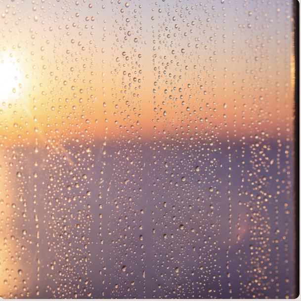 Beautiful water droplets on window glass with sunset colors